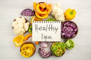 top view healthy life written notebook cut green tomatoes cut red cabbage cut pumpkin cauliflower cut bell peppers bowls wooden surface scaled