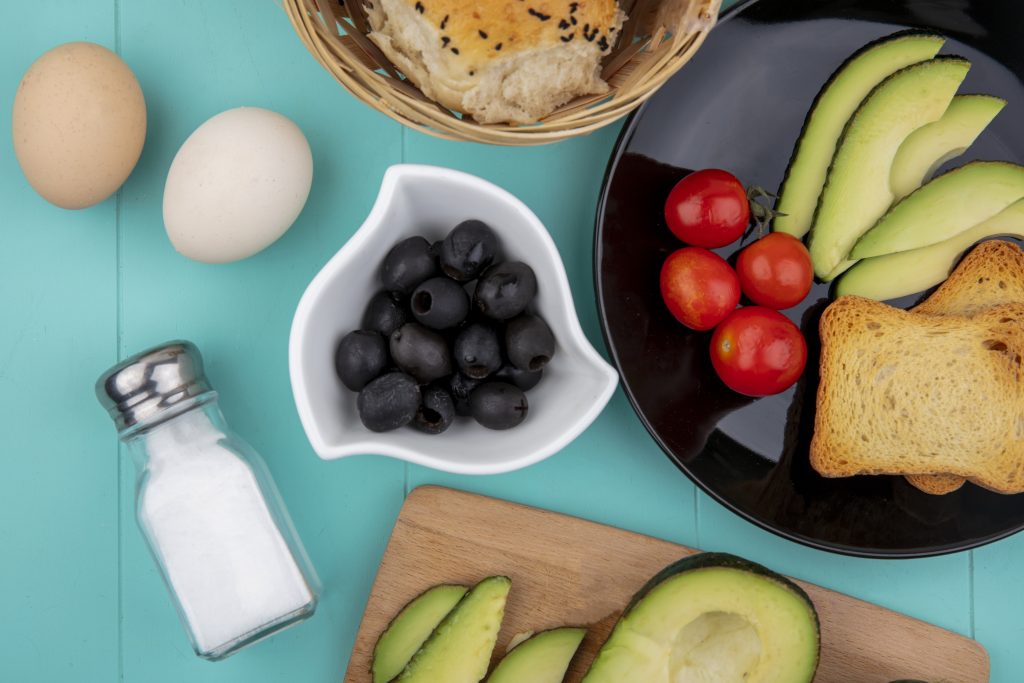 top view black olives white bowl with vegetables like tomatoes avocado slice black plate bucket breads blue scaled