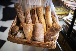 close up baker holding basket with bread sticks scaled